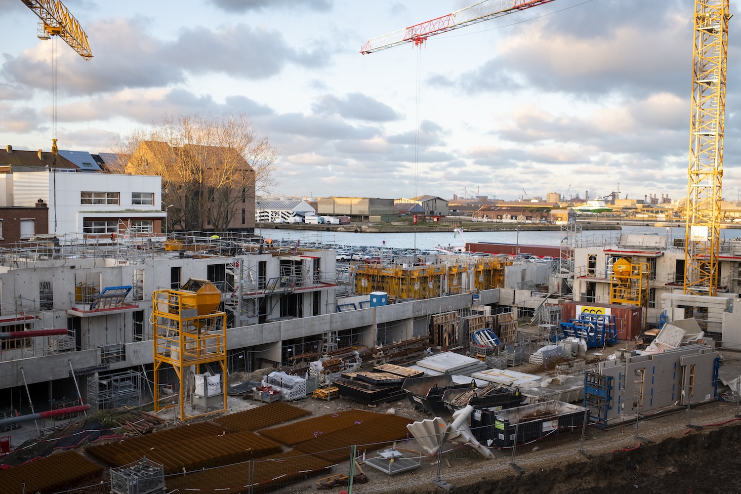 Chantier de construction urbain avec grues, bâtiments en construction et ciel nuageux.