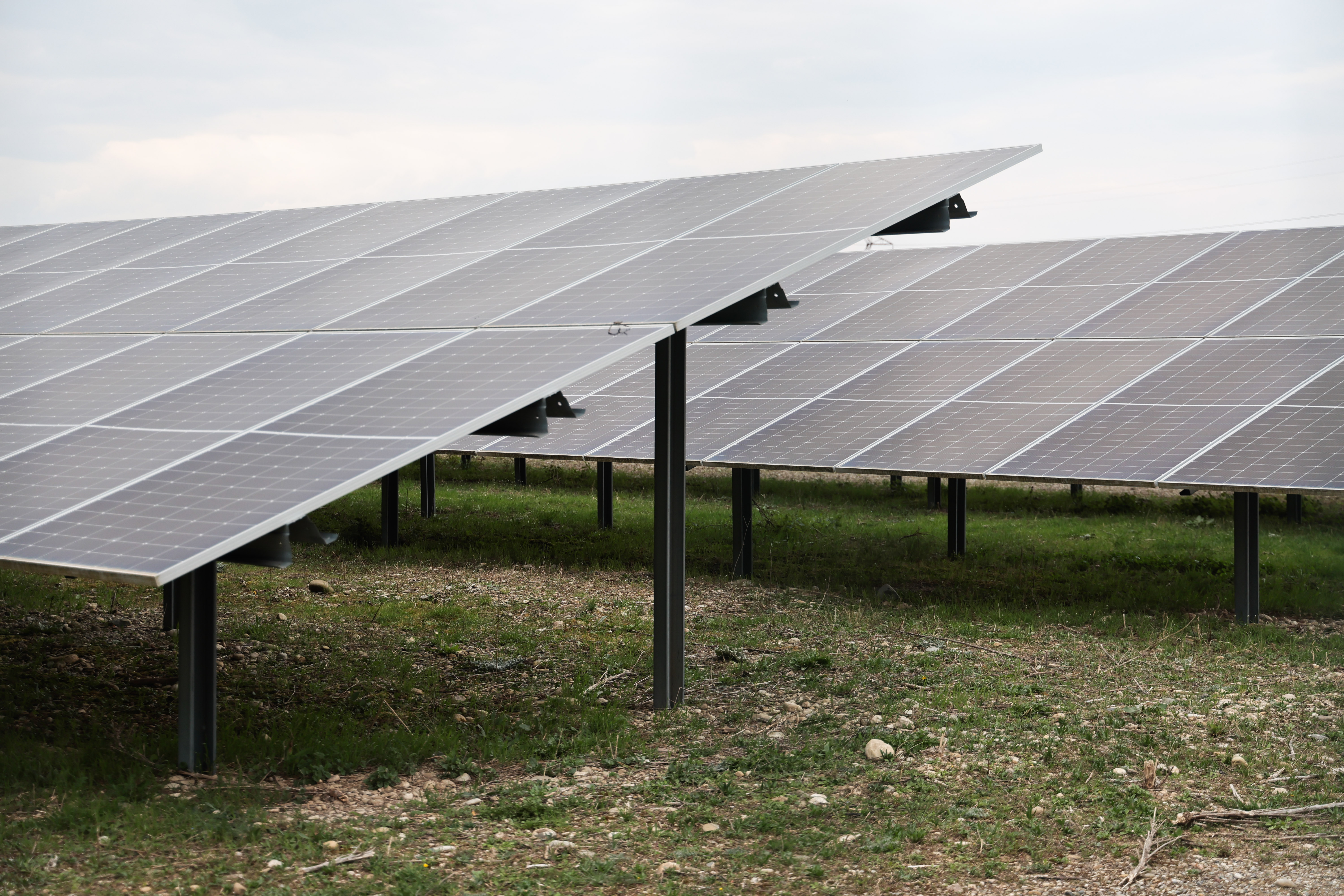 Panneaux solaires installés sur un terrain herbeux sous un ciel légèrement nuageux.