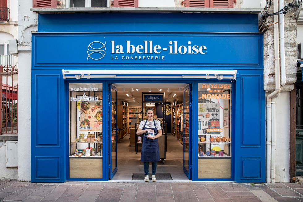 Devanture de la boutique La Belle-Iloise avec une personne en tablier à l'entrée.