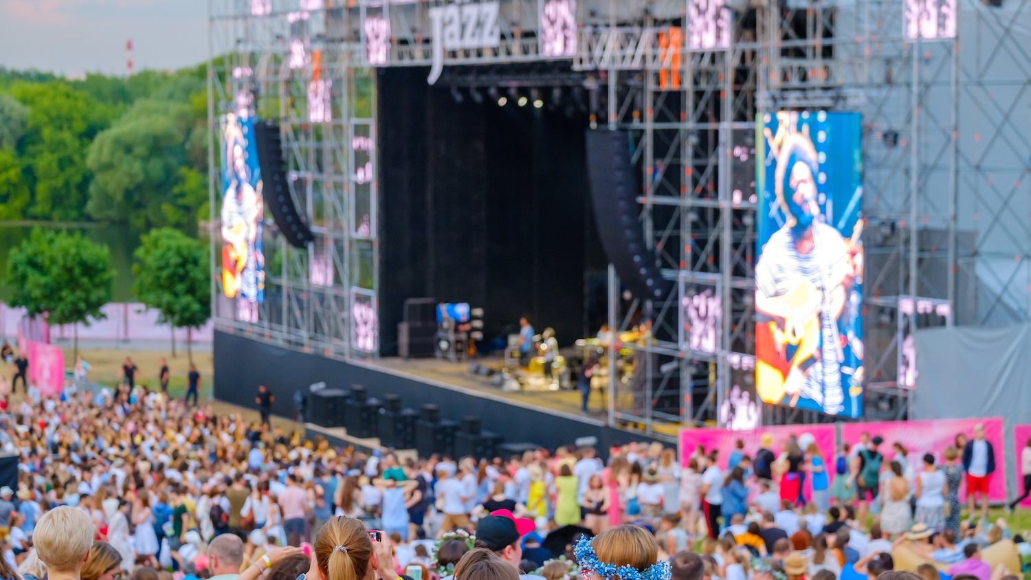 Concert en plein air avec foule nombreuse et scène illuminée en arrière-plan.