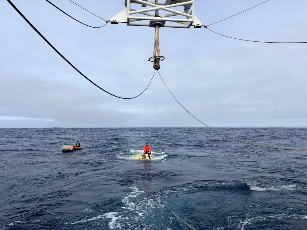 Personne en mer avec gilet de sauvetage près d'un bateau et d'une corde suspendue