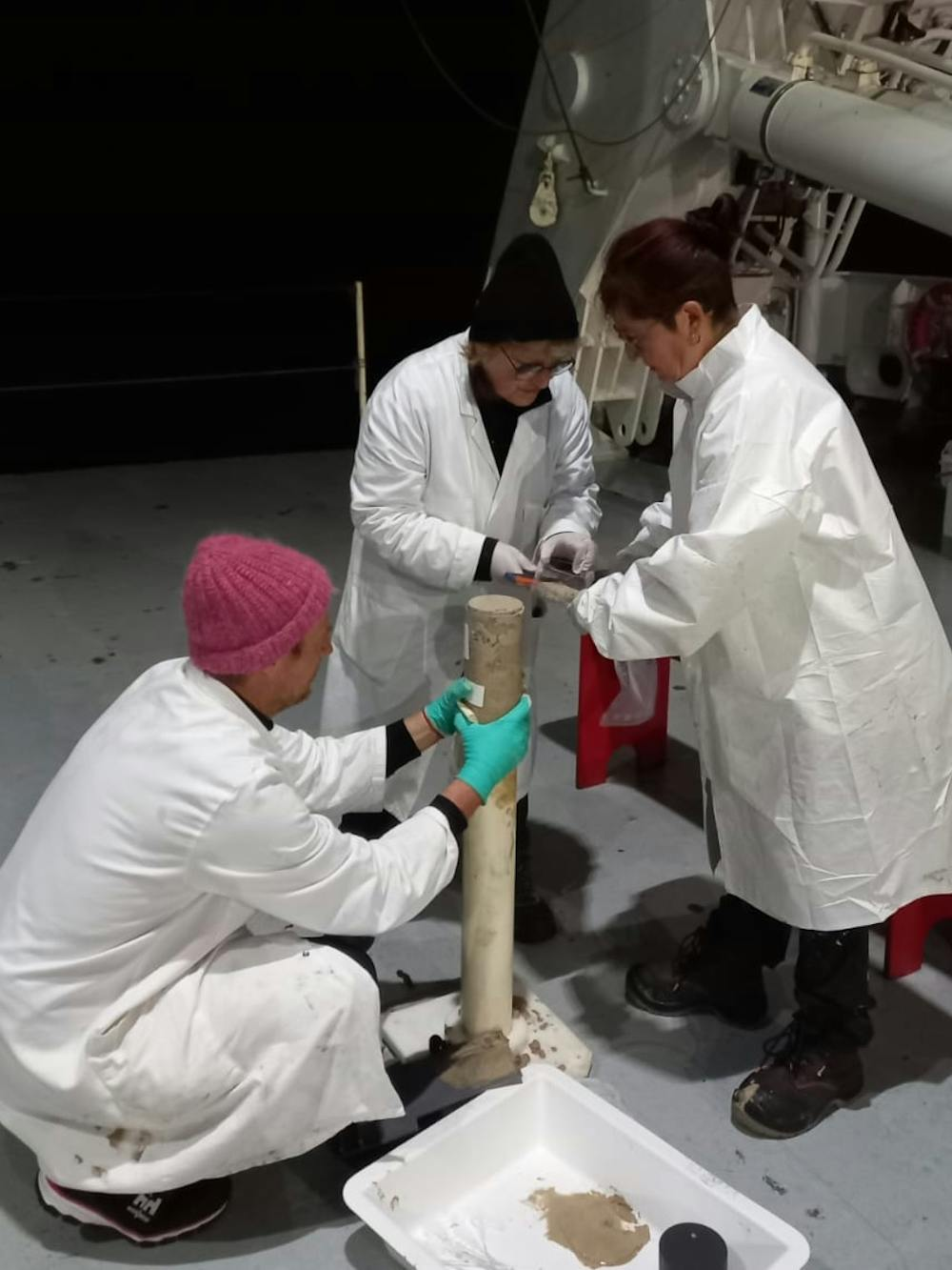 Des personnes en blouses blanches travaillent ensemble sur un objet à l'extérieur.