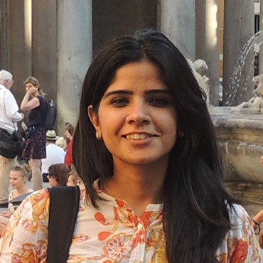 Femme souriante devant une fontaine avec des touristes en arrière-plan