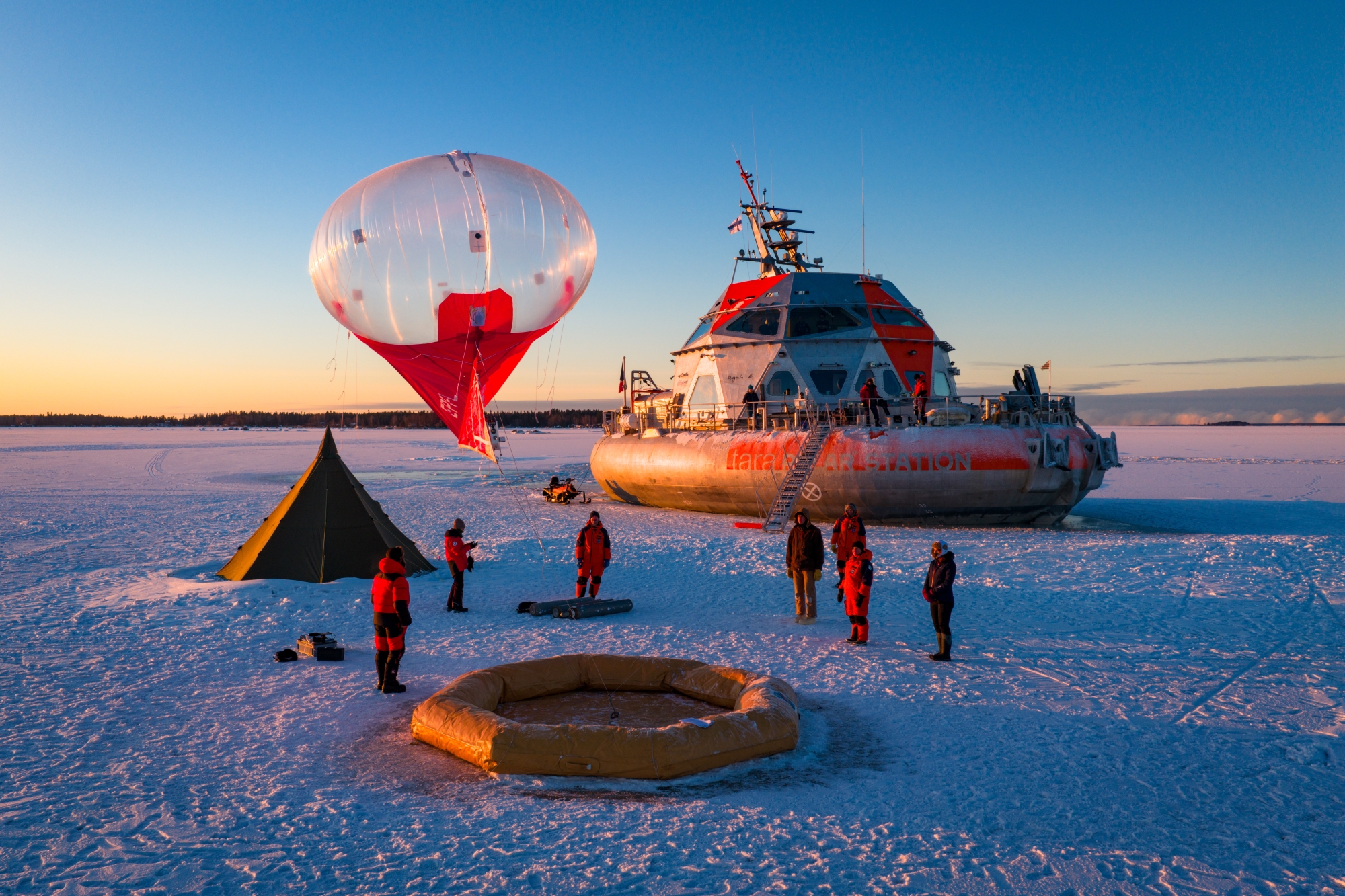 Expédition polaire avec ballon, tente et véhicule sur la glace au coucher du soleil.