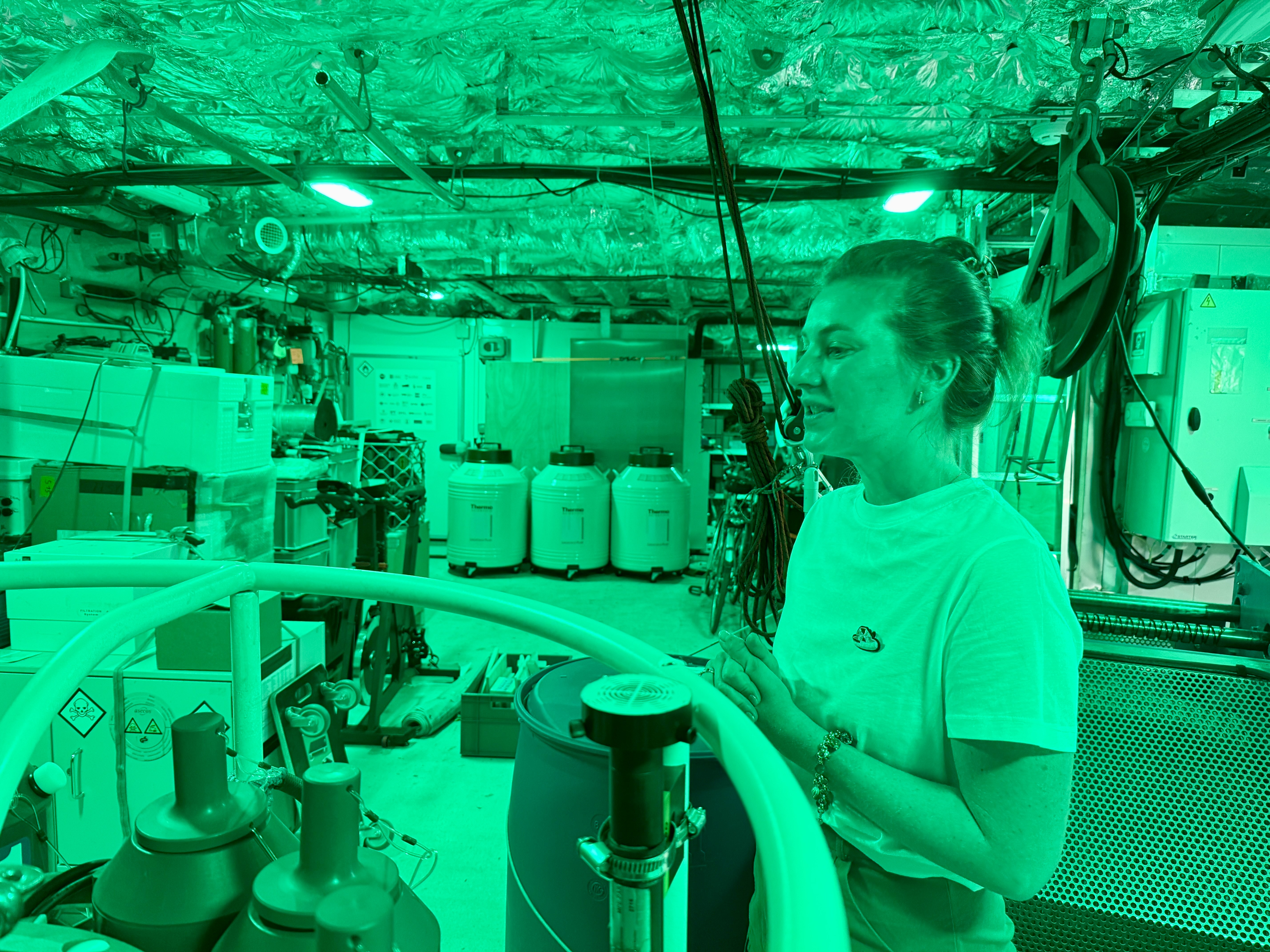 Personne travaillant dans un environnement technique avec équipement et éclairage vert intense.