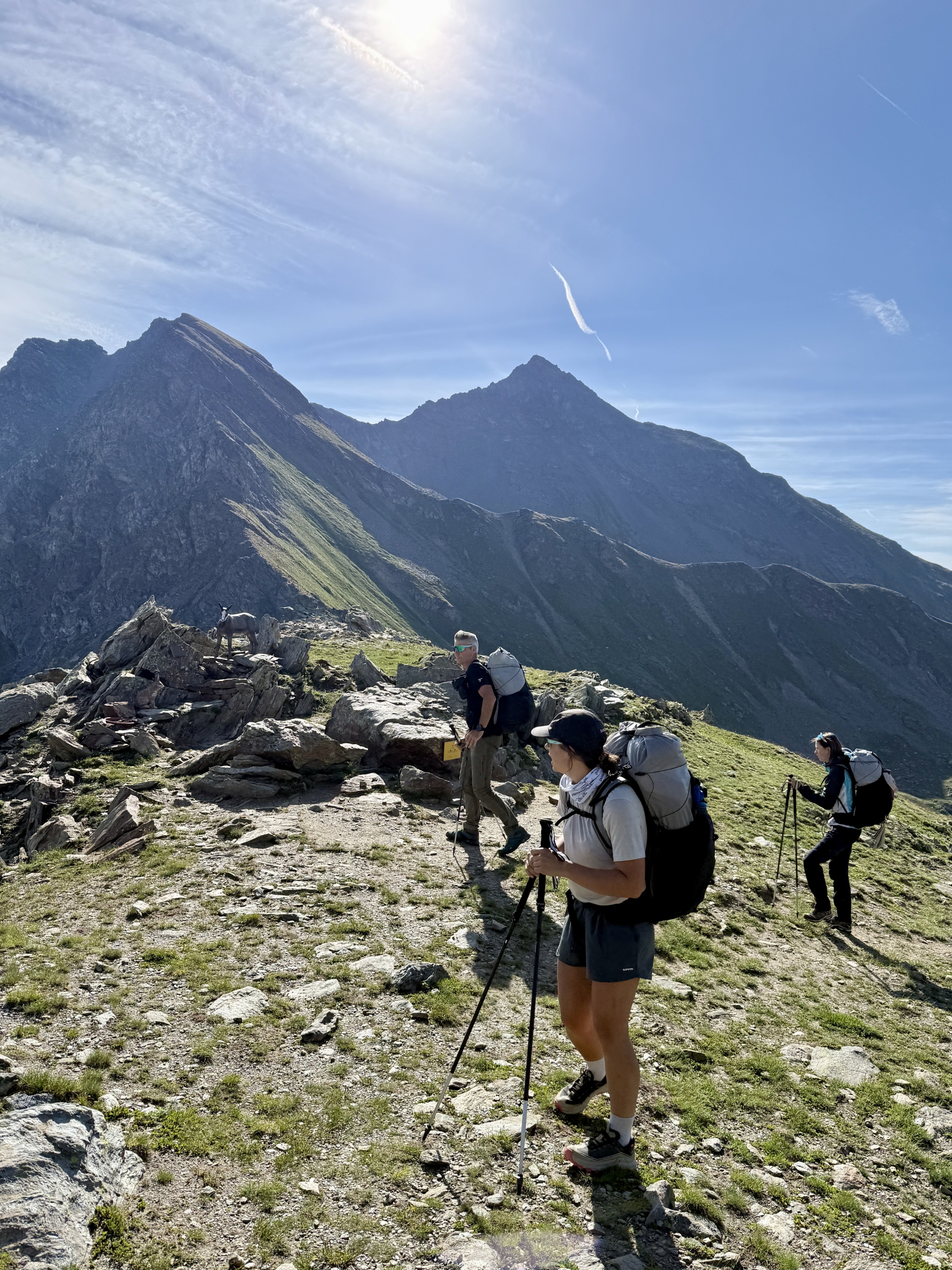 Randonneurs avec sacs à dos marchant sur un sentier montagneux avec vue panoramique.