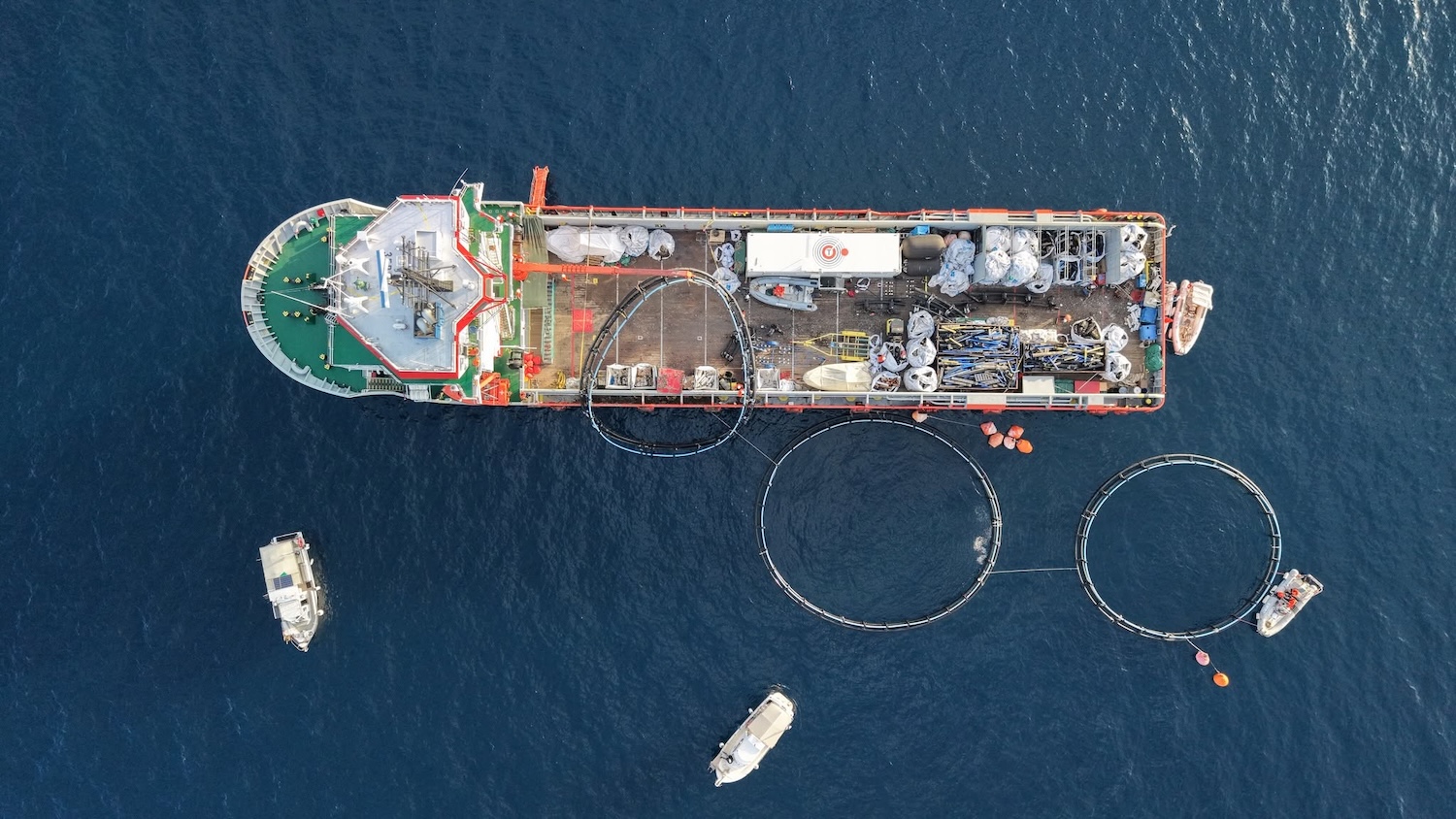 Vue aérienne d'un navire en mer avec des cercles et des bateaux autour.