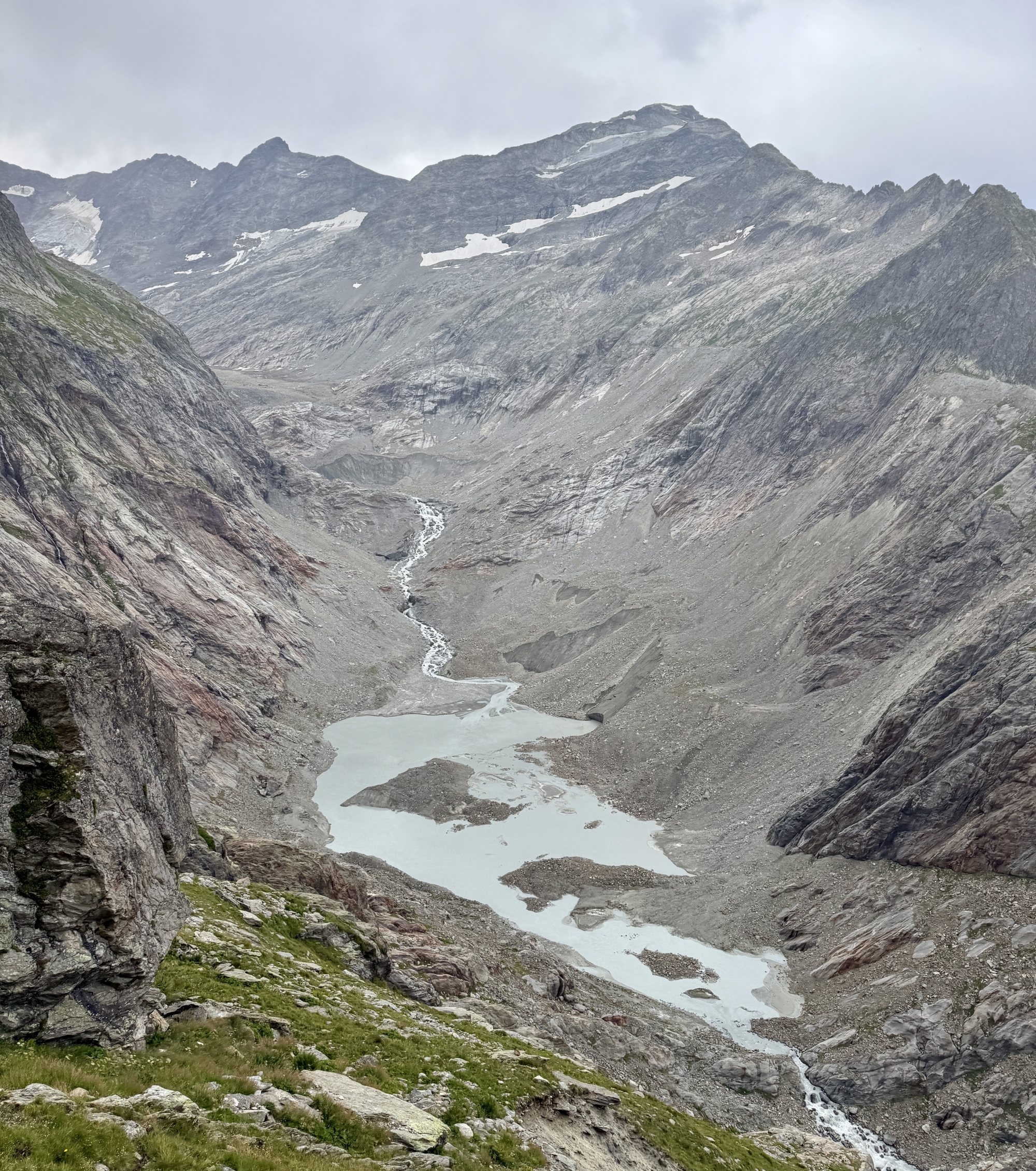 Vallée glaciaire rocheuse avec une rivière sinueuse et un petit lac à l'avant-plan.