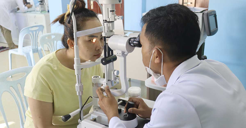 Examen ophtalmologique avec un médecin et une patiente utilisant une lampe à fente.