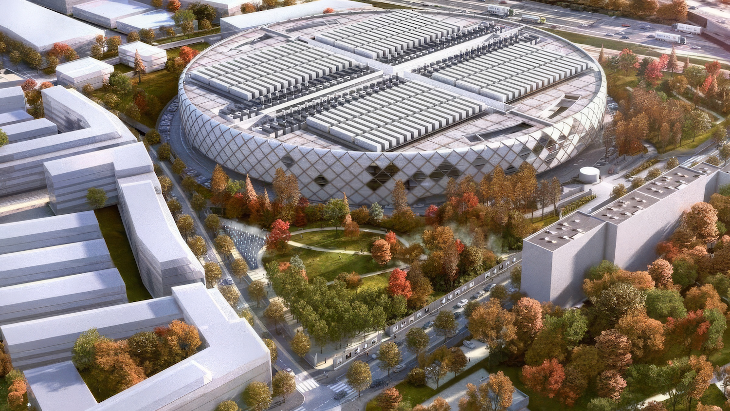 Vue aérienne d'un bâtiment circulaire moderne entouré de verdure et d'arbres en automne.