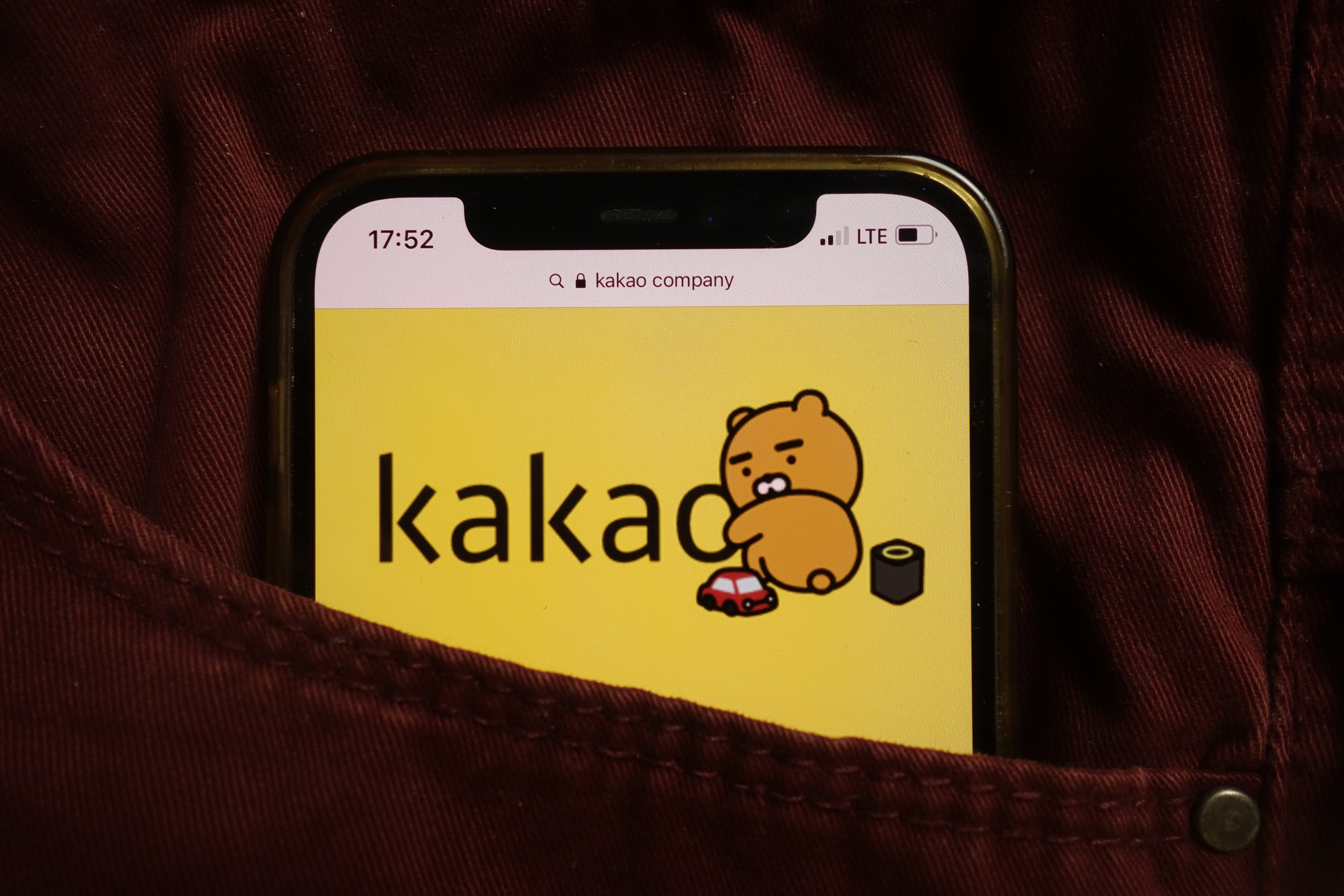Écran de smartphone affichant le logo Kakao avec un personnage cartoon sur fond jaune.