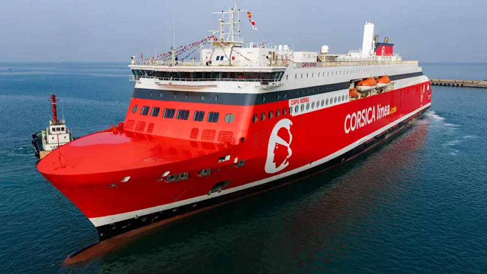Un ferry rouge de Corsica Ferries naviguant en mer près d'un port.