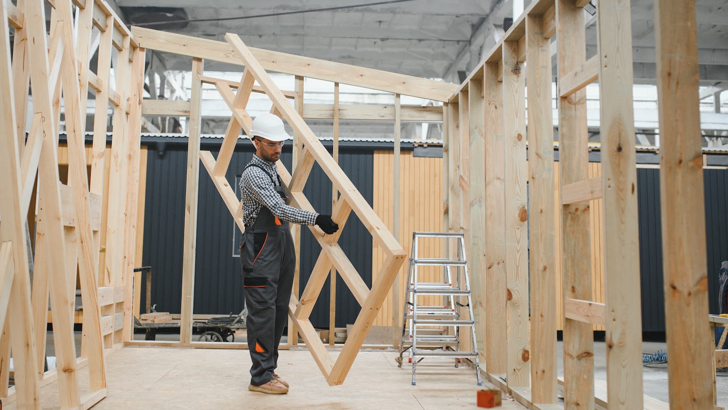 Un ouvrier en construction installe un cadre en bois dans un bâtiment en construction.