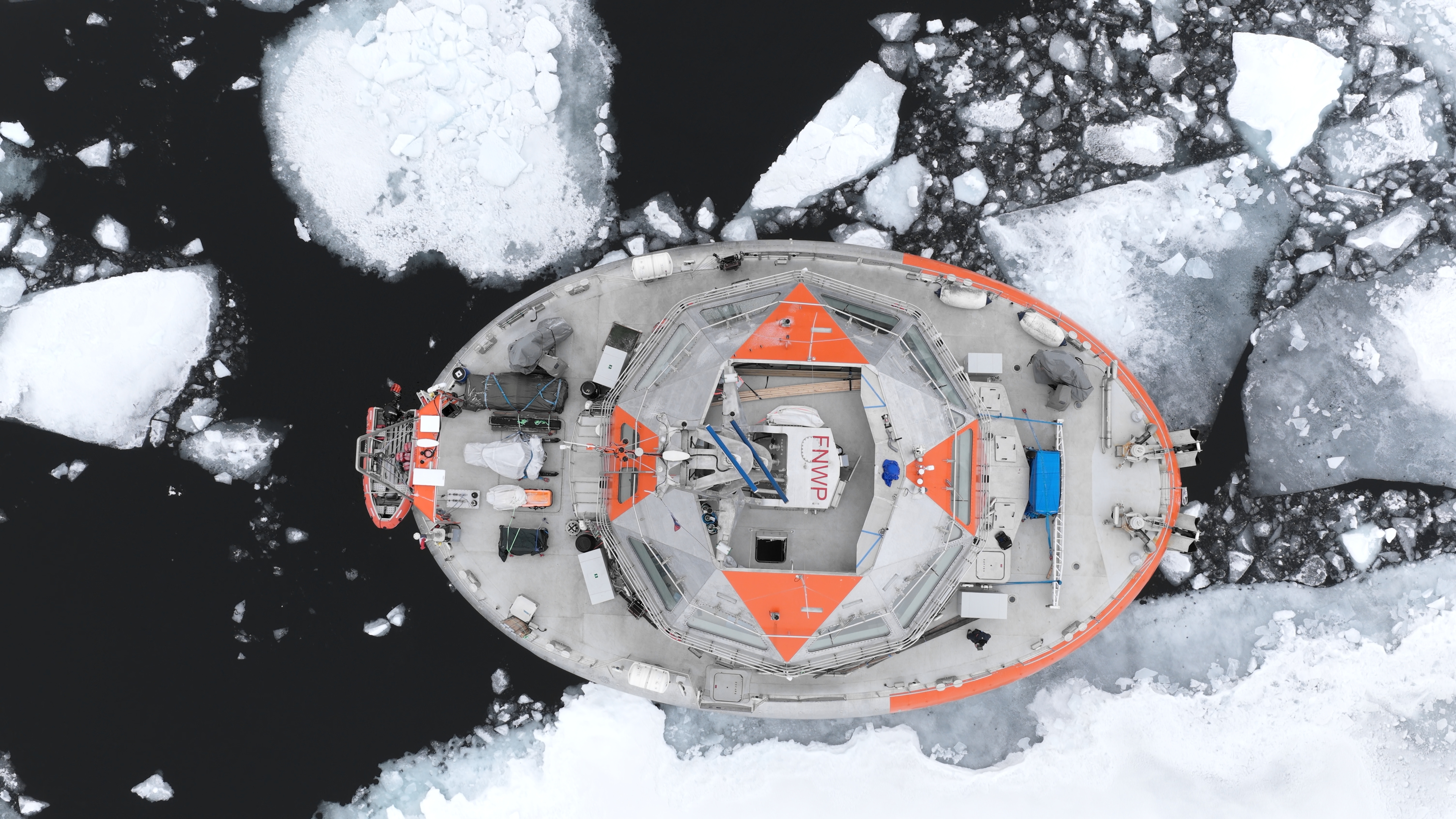 Vue aérienne d'un brise-glace naviguant à travers des blocs de glace flottants dans l'Arctique.