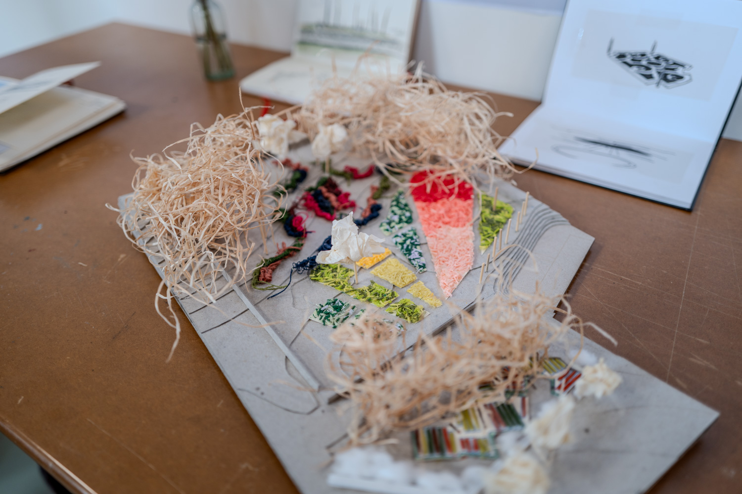 Maquette artistique avec matériaux naturels et colorés sur une table en bois.