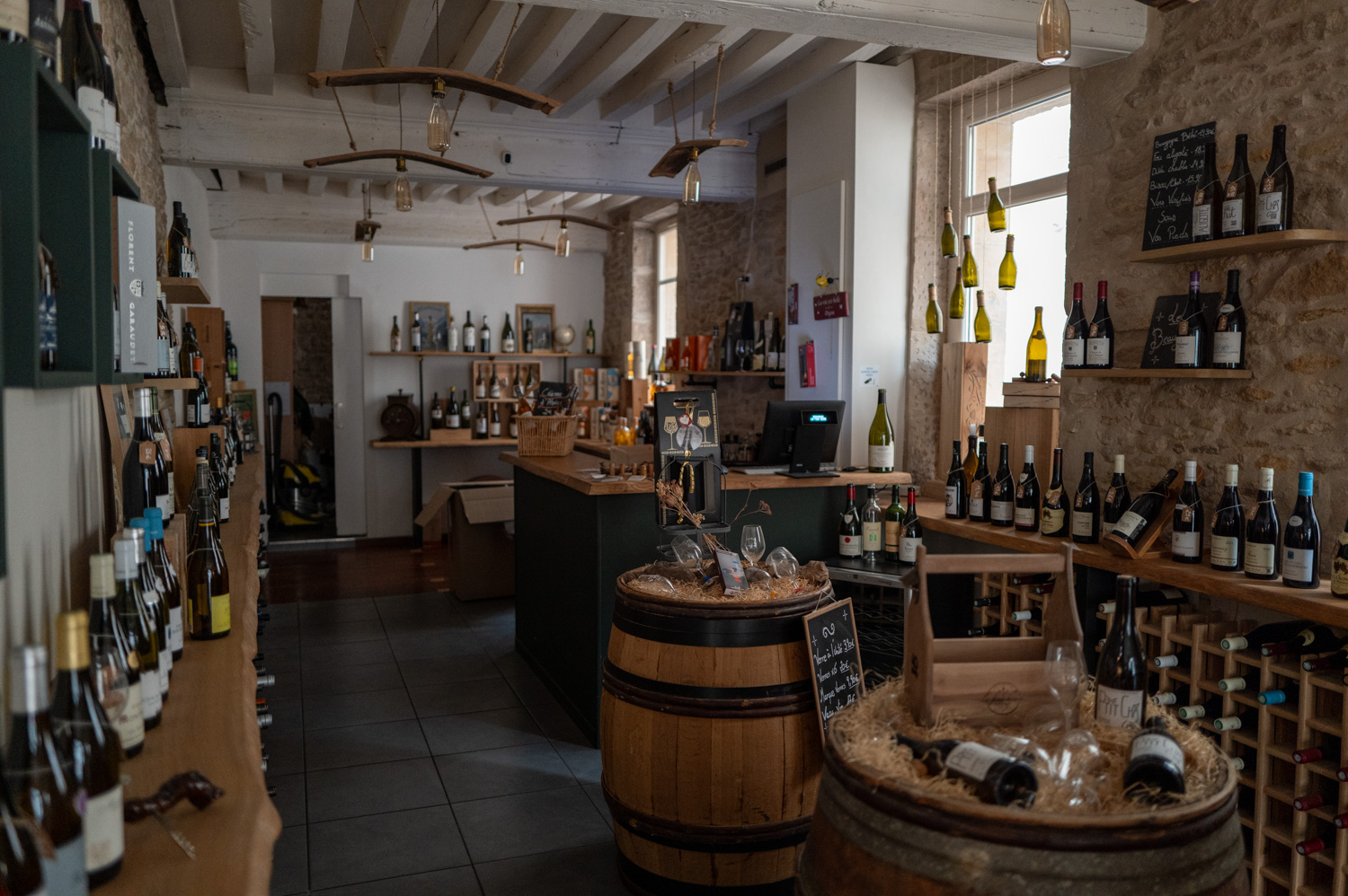 Un magasin de vins avec des bouteilles exposées sur des étagères et des tonneaux.