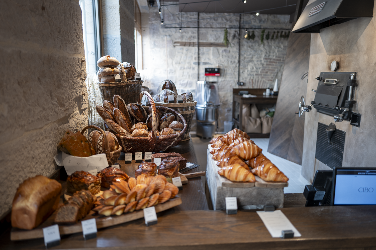 Boulangerie avec divers pains et viennoiseries exposés sur un comptoir en bois rustique.